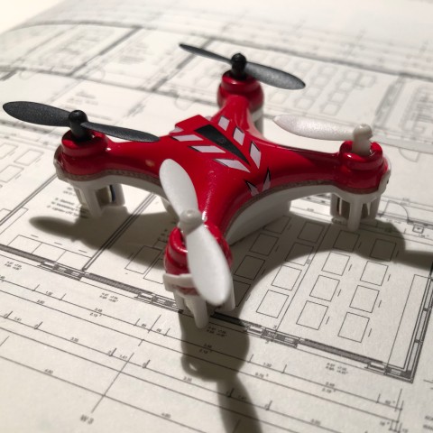 Rød og hvid drone ovenpå en teknisk tegning