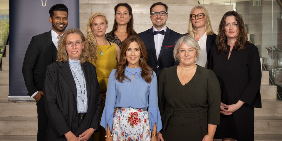 Se syv modtagere af Undervisningsprisen 2024 sammen med Dronning Mary og uddannelsesminister Christina Egelund - Juljana Jacobsen står i bagerste rækkemed langt mørkt hår