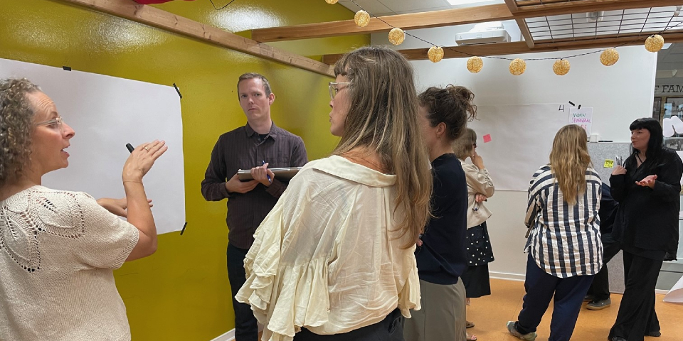 Mennesker der står ved tavle til workshop