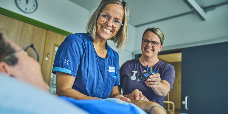 To sygeplejersker snakker med person i seng
