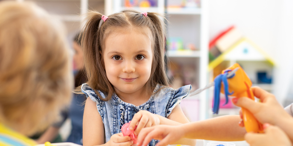 Små børn leger med modellervoks ved et bord